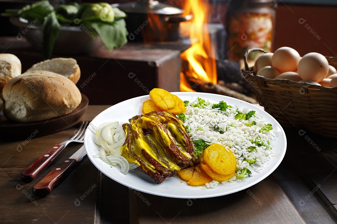 Bife grelhado com batata e arroz em um prato sobre mesa de madeira