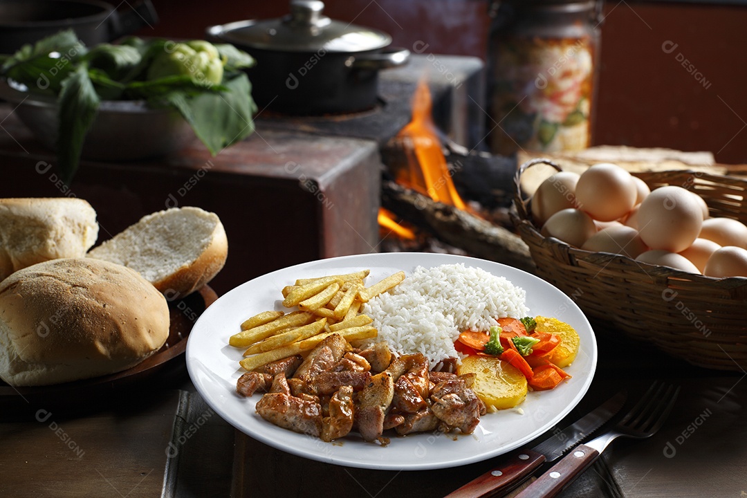 Bife grelhado com batata e arroz em um prato sobre mesa de madeira