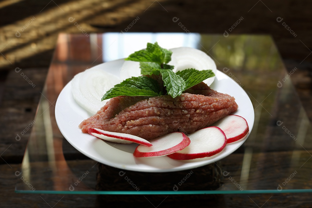 Quibe cru em um prato sobre mesa de madeira