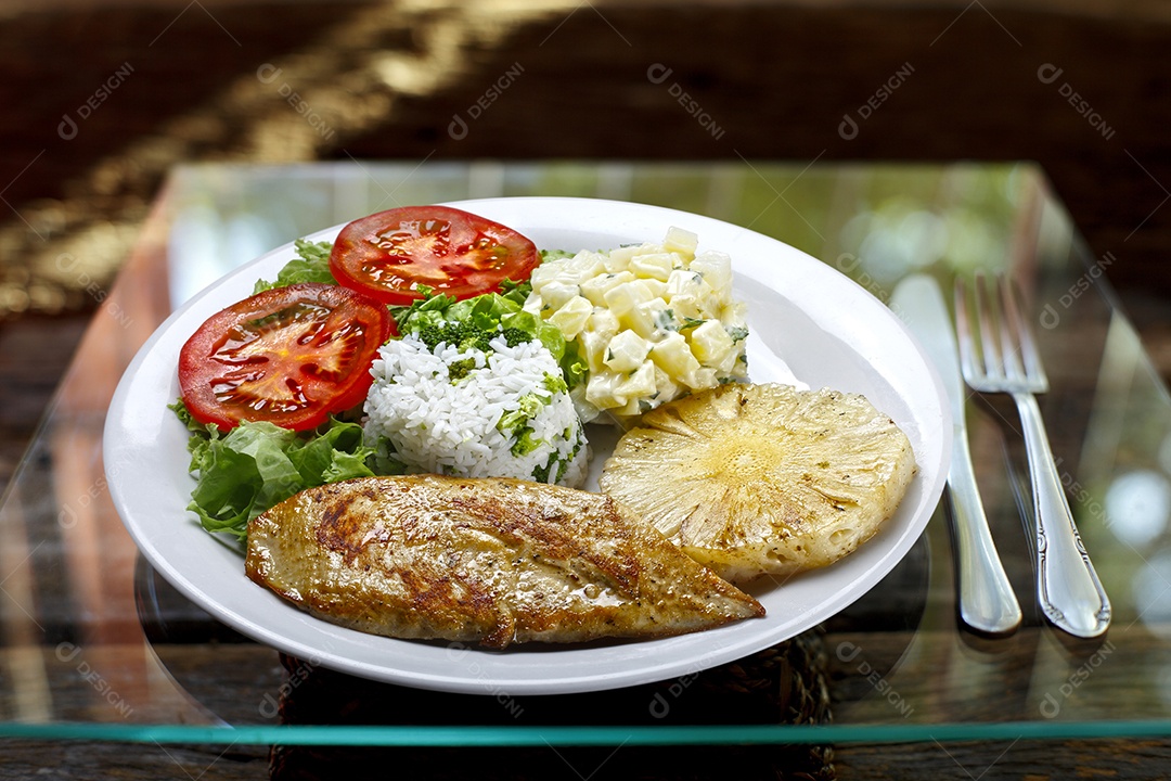 Bife de frango grelhado em um prato sobre mesa de vidro