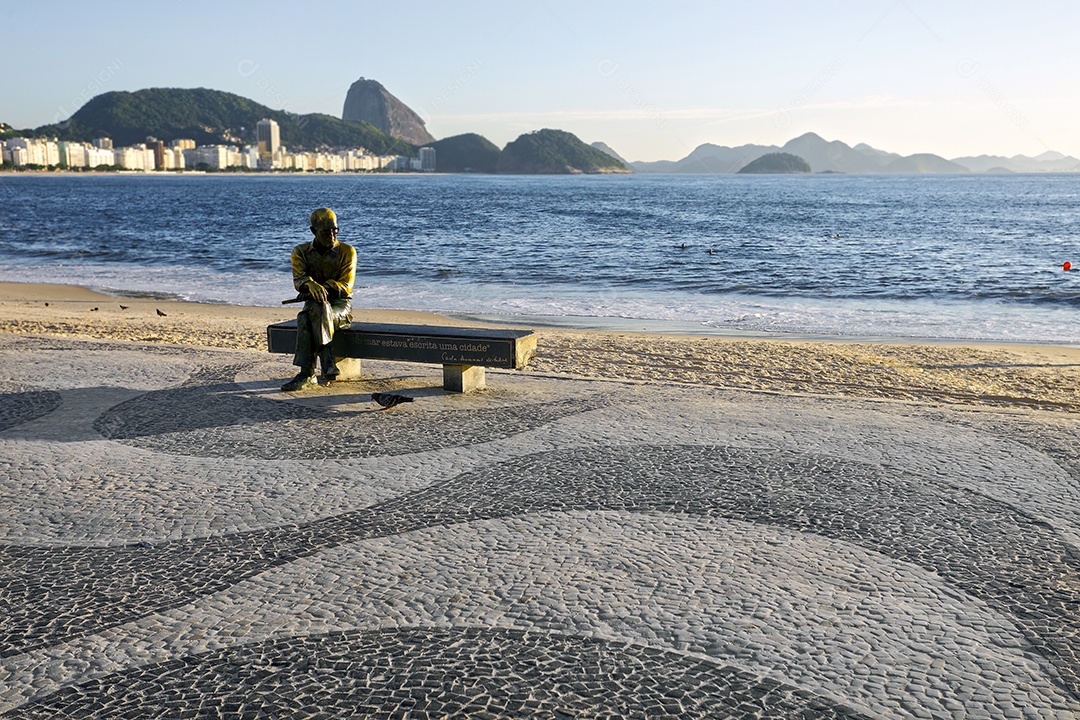 Estátua em um banco com frase de costa para o mar