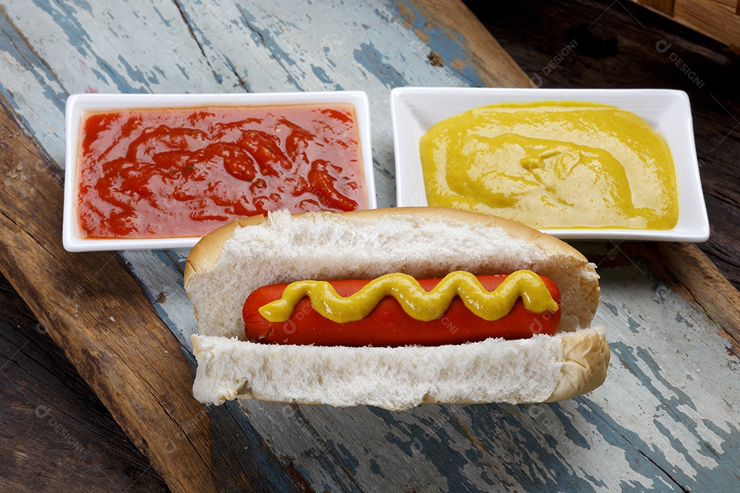 Tábua de madeira com cachorro quente e ketchup mostarda