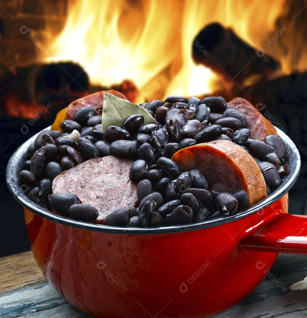 Panela com feijão e calabresa sobre fundo de fogo