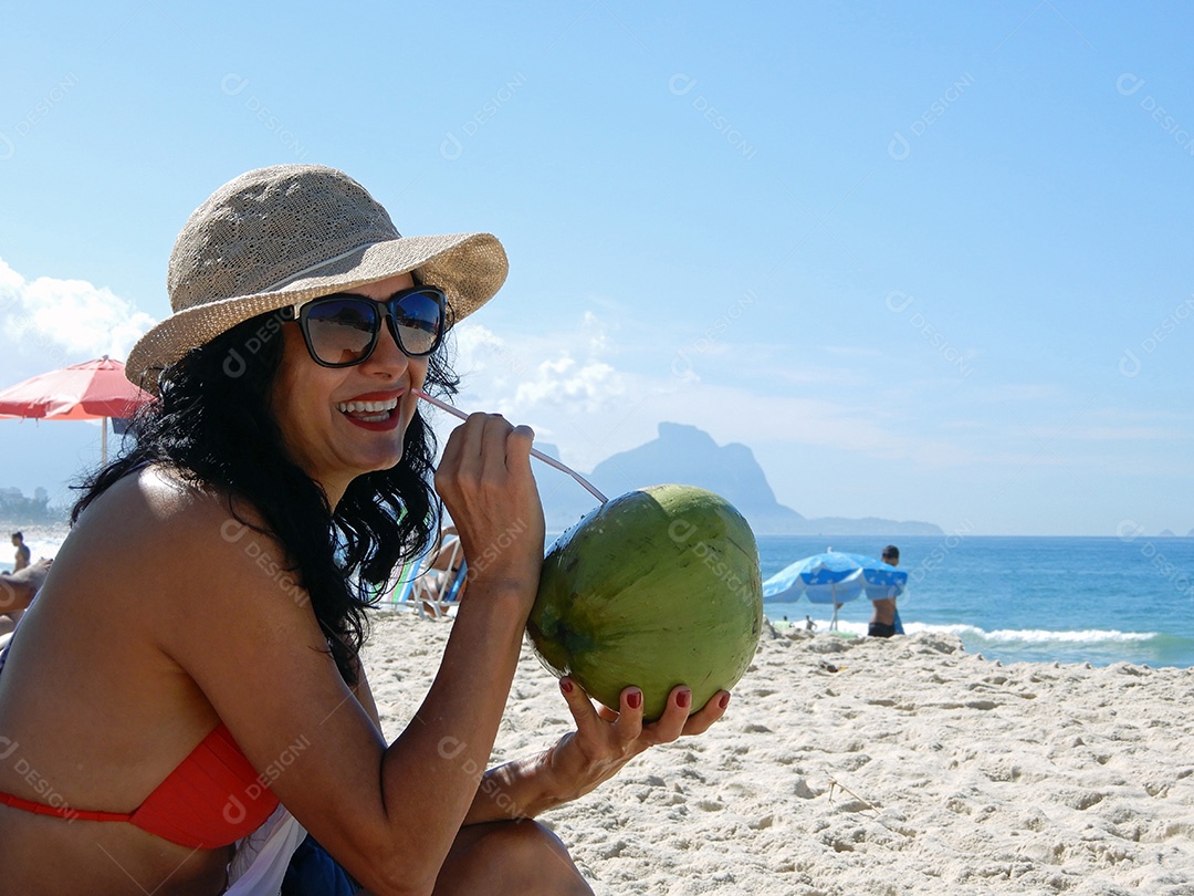 Mulher na praia bebendo água de coco no Rio de Janeiro