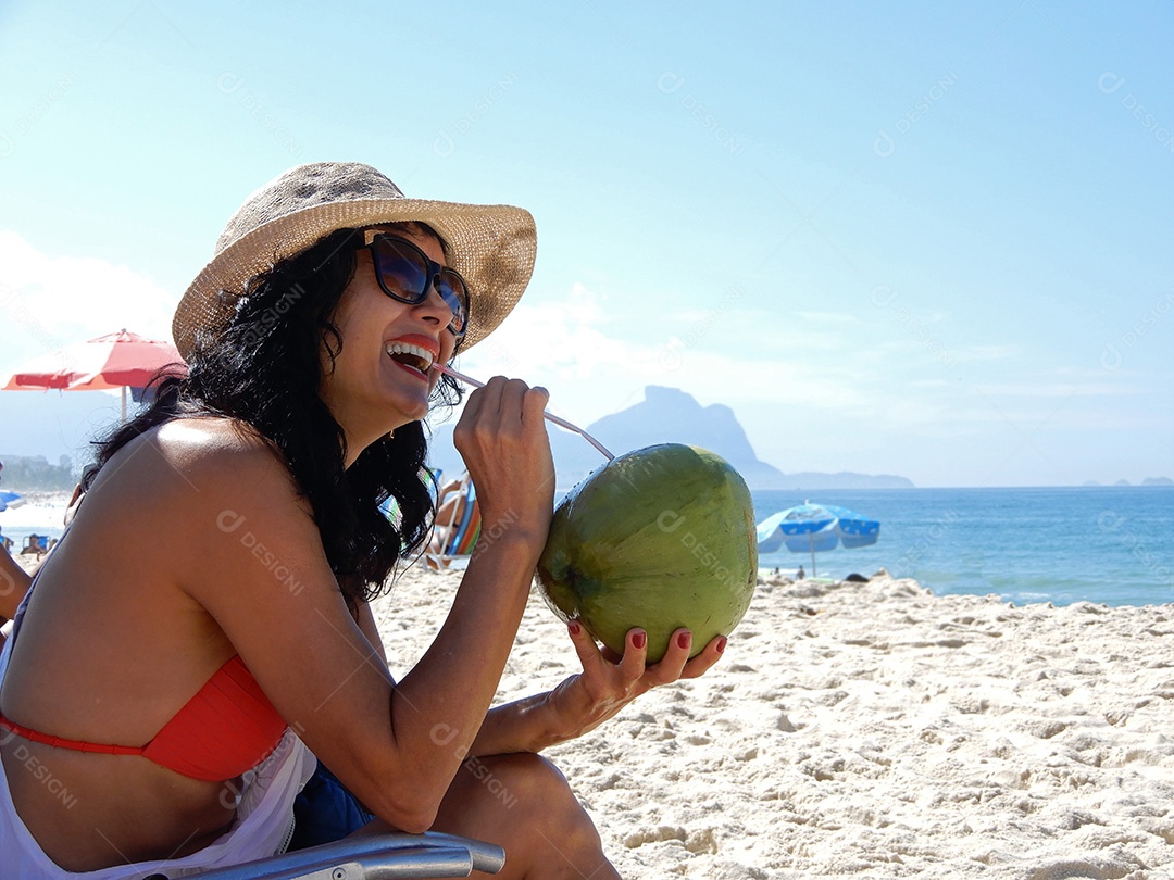 Mulher na praia bebendo água de coco no Rio de Janeiro