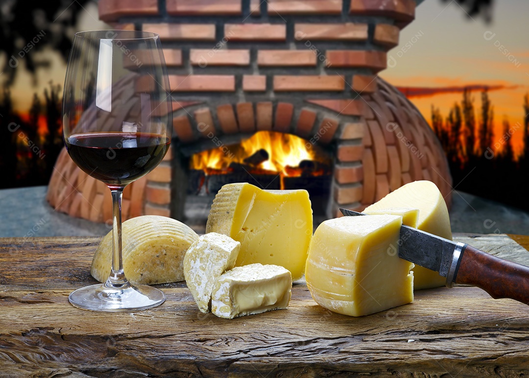 Queijos sobre uma tábua de madeira e taça de vinho