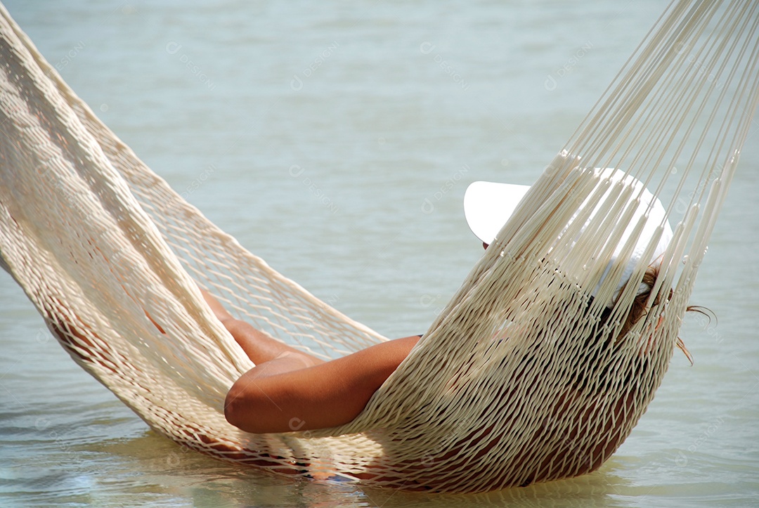 Uma turista deitada na rede de uma praia