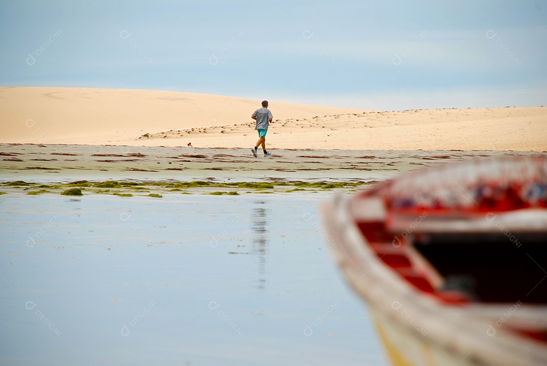 Barco ancorado e uma pessoa correndo na areia