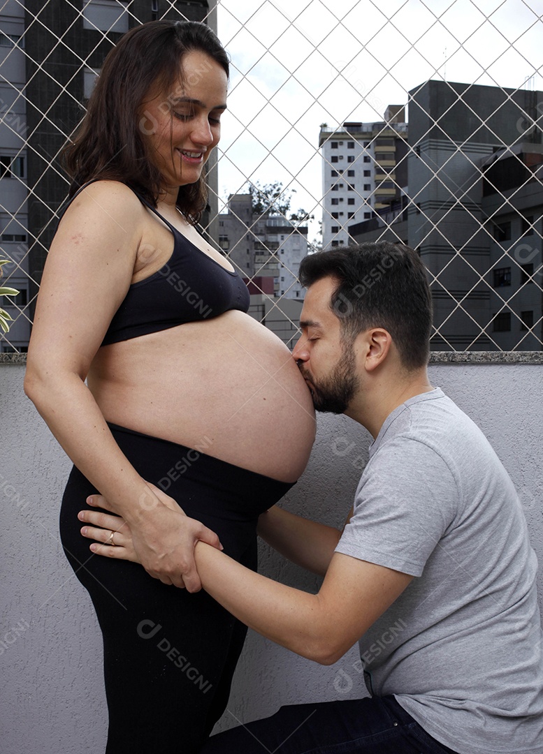 Lindo casal homem beijando barriga de esposa grávida