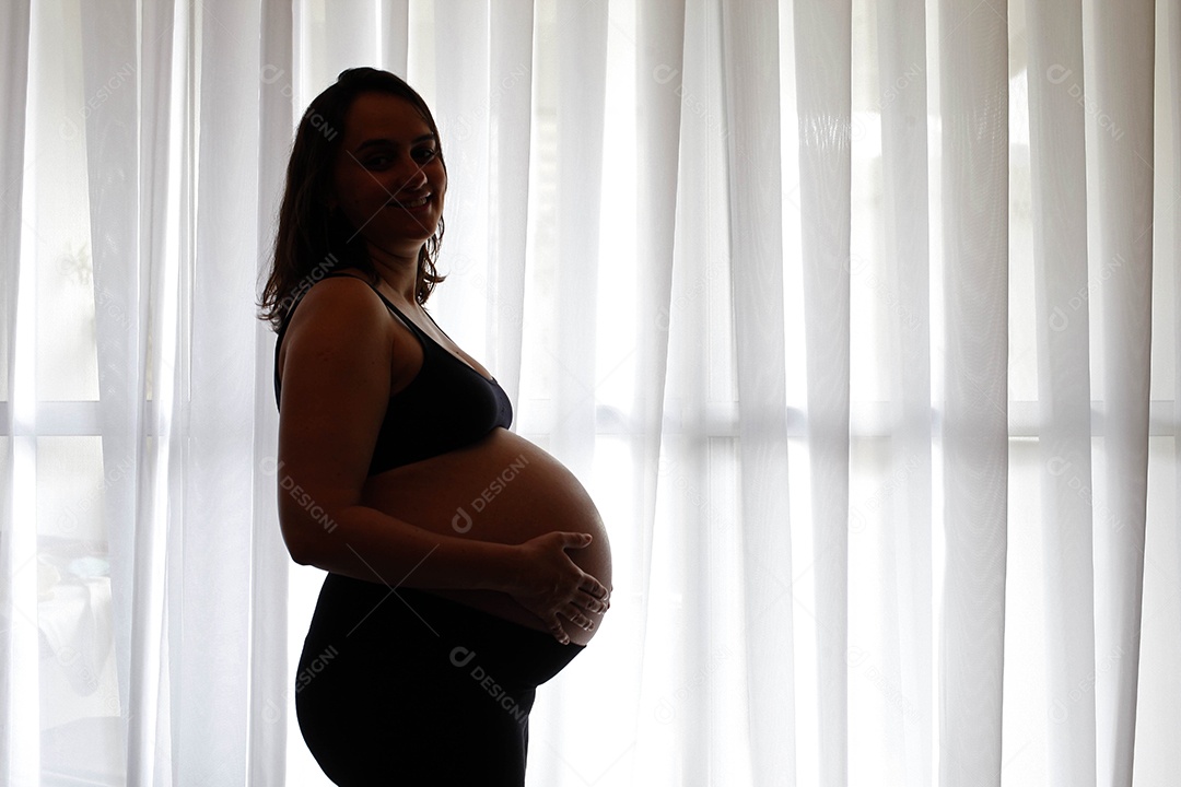 Linda mulher com mãos na sua barriga de gravida