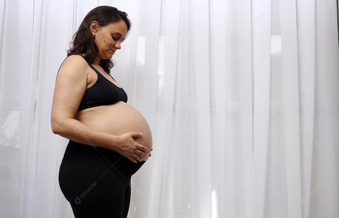 Mulher com mãos na sua barriga de bebê lindo