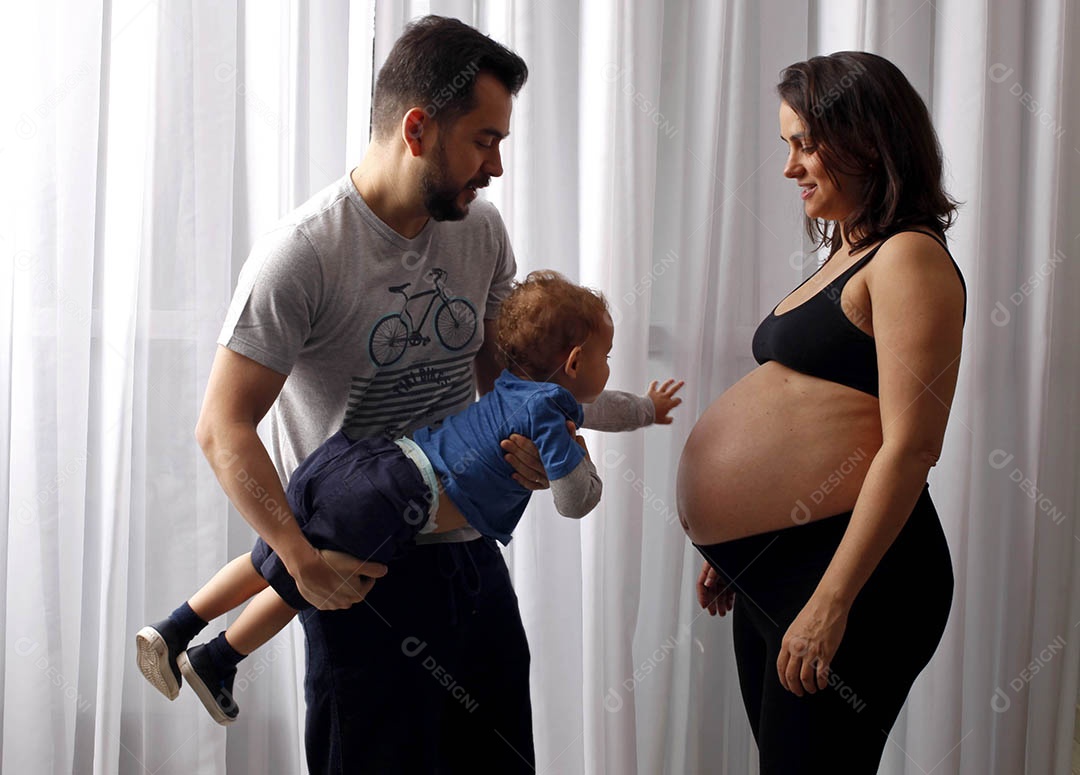 Família linda pai segurando seu filho e mãe grávida em ensaio fotografico