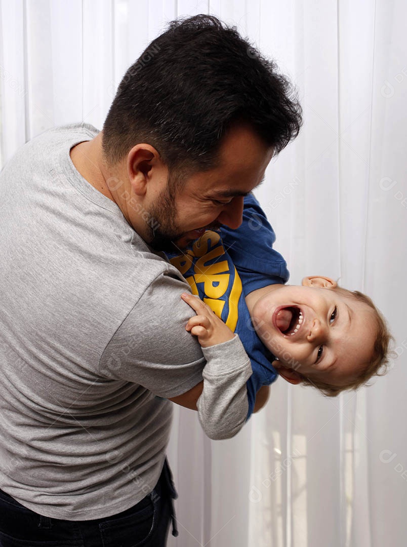 Um homem sorrindo se divertindo com seu bebê