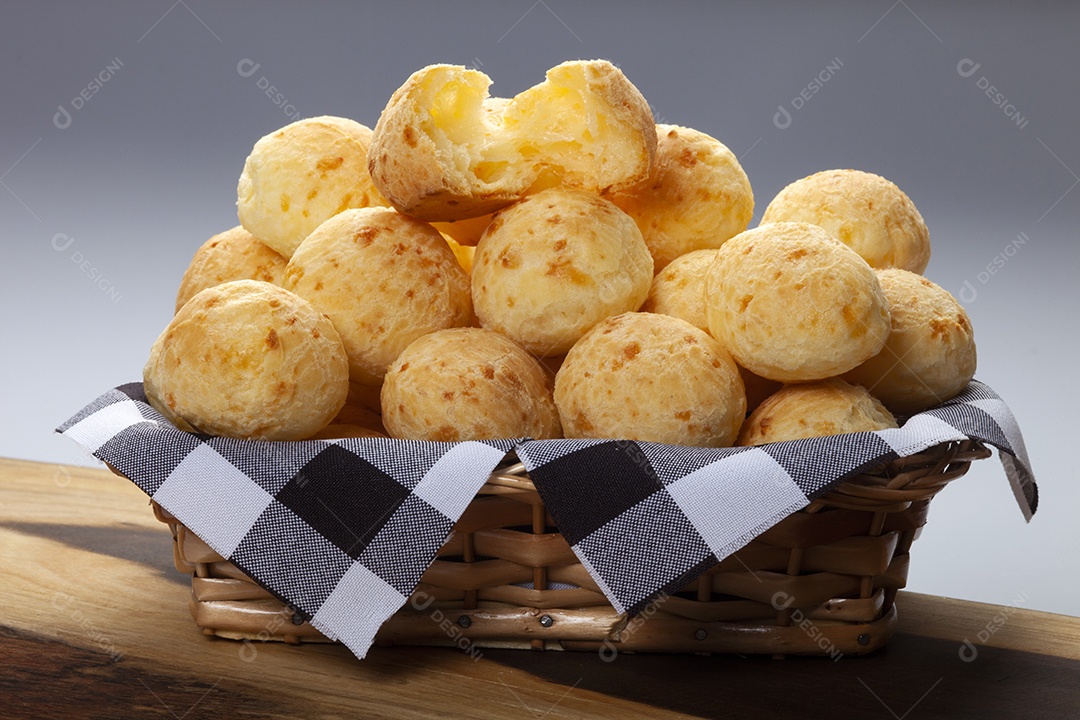 Cesta com pães de queijo delicioso sobre uma mesa de madeira