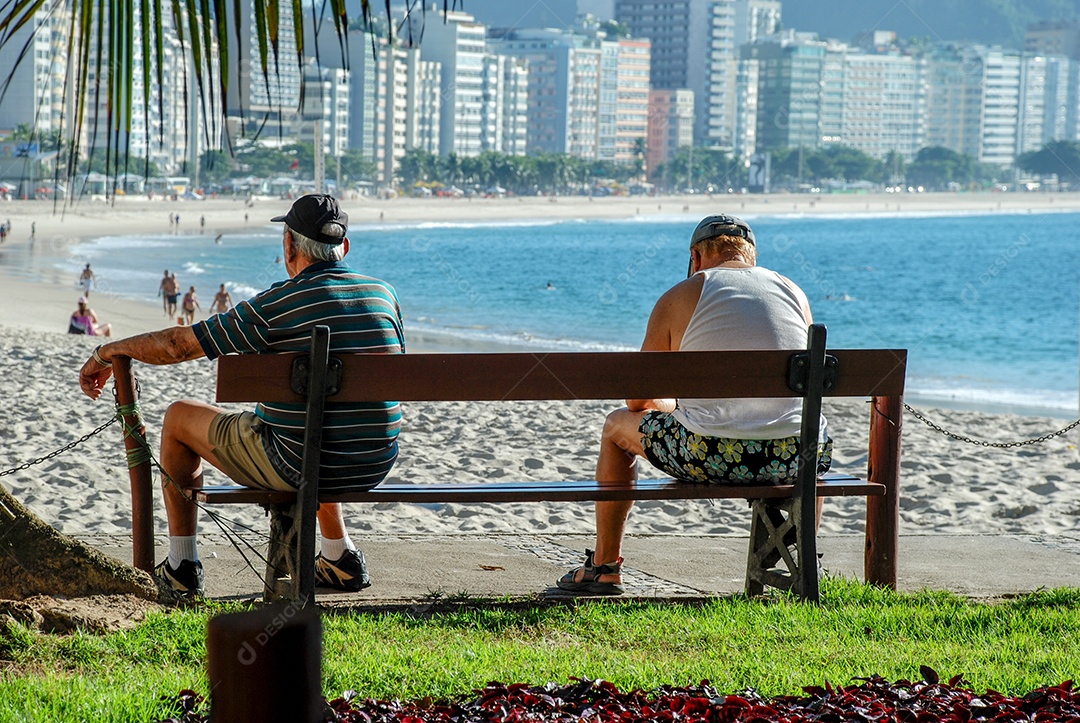 Dois idosos sentados no banco da praia de Copacabana