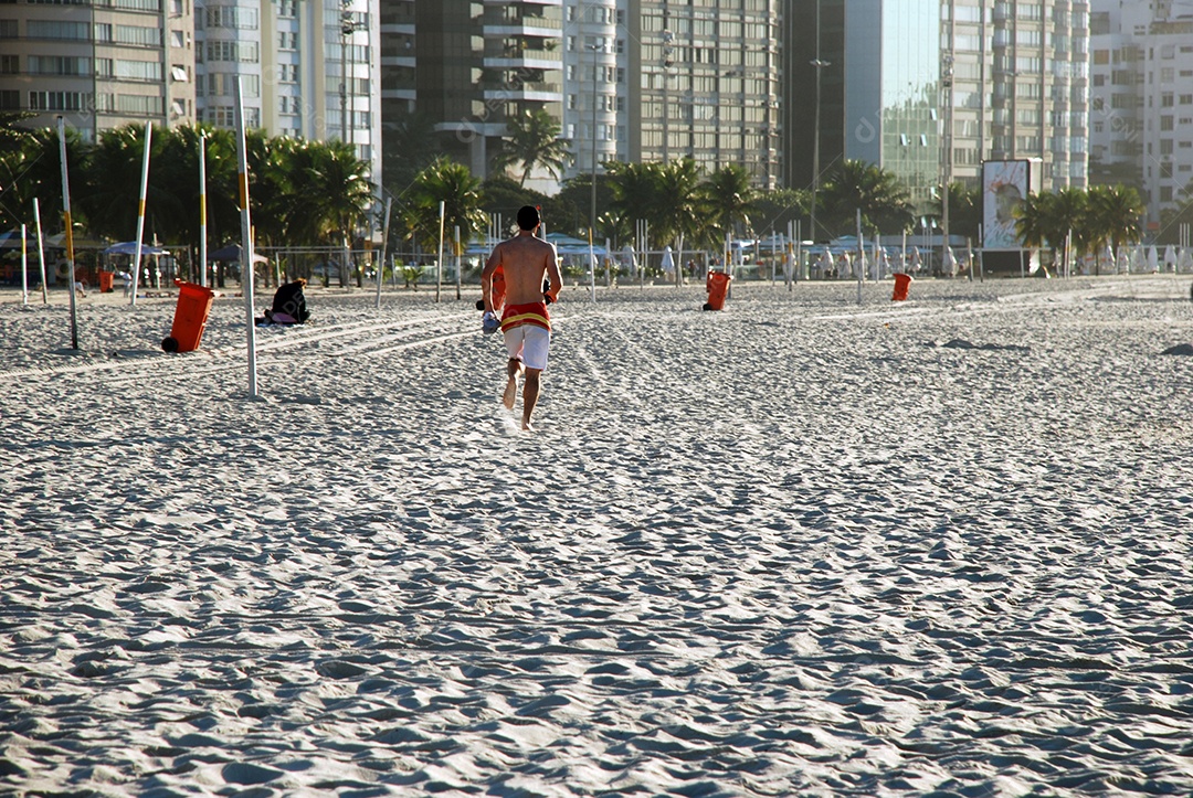 Um rapaz correndo na areia da praia