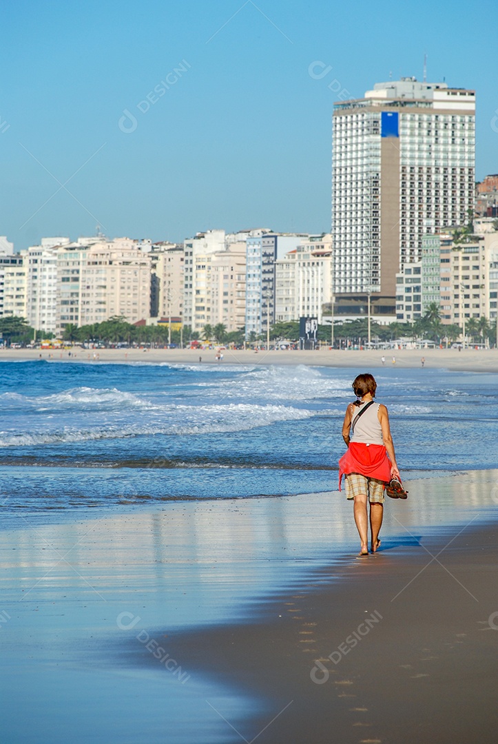 Mulher fazendo uma caminhada na areia da praia