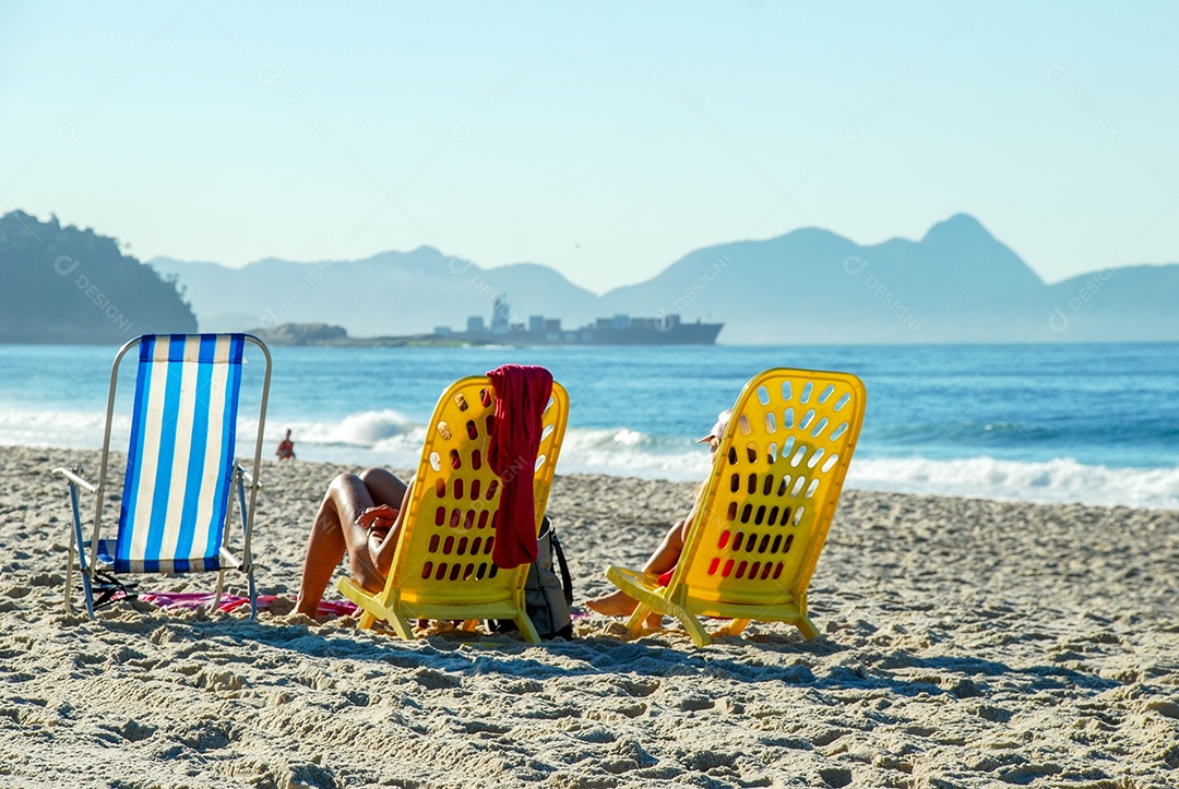 Pessoas na praia de Copacabana sentadas na cadeira de praia