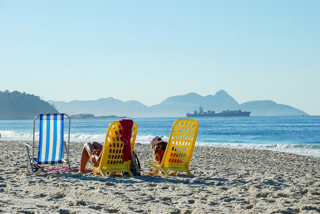 Pessoas na praia de Copacabana sentadas na cadeira de praia