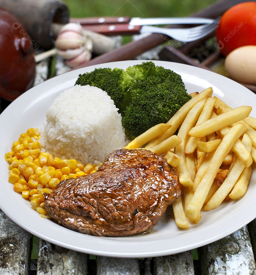 O bife à parmegiana com batata e arroz em um prato sobre fundo isolado