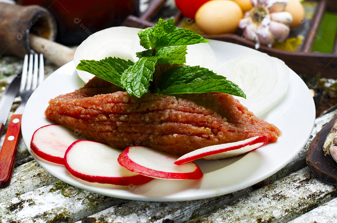 Quibe cru em um prato sobre mesa de madeira