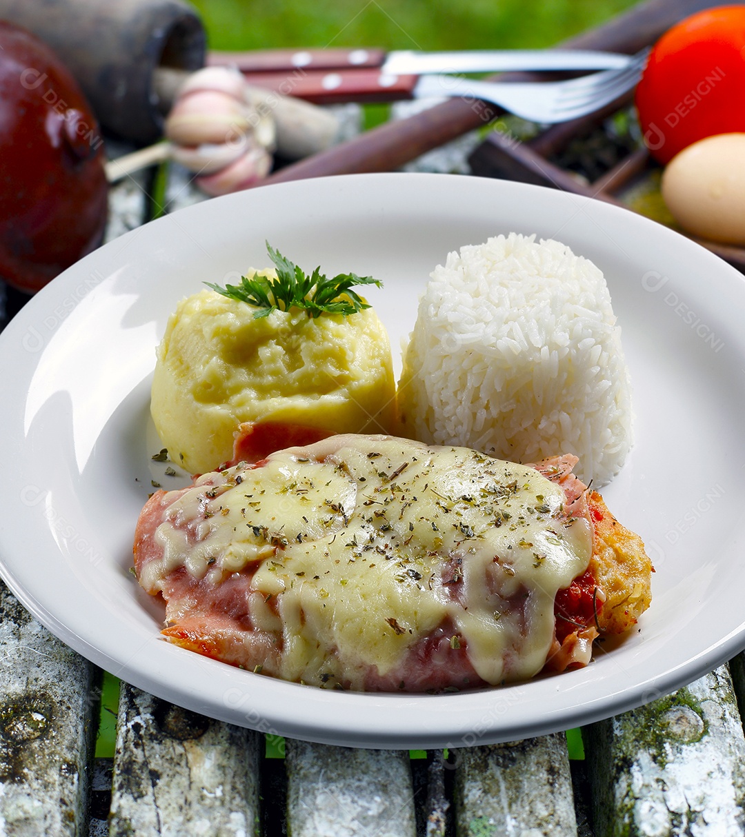 O bife à parmegiana com batata e arroz em um prato sobre fundo isolado
