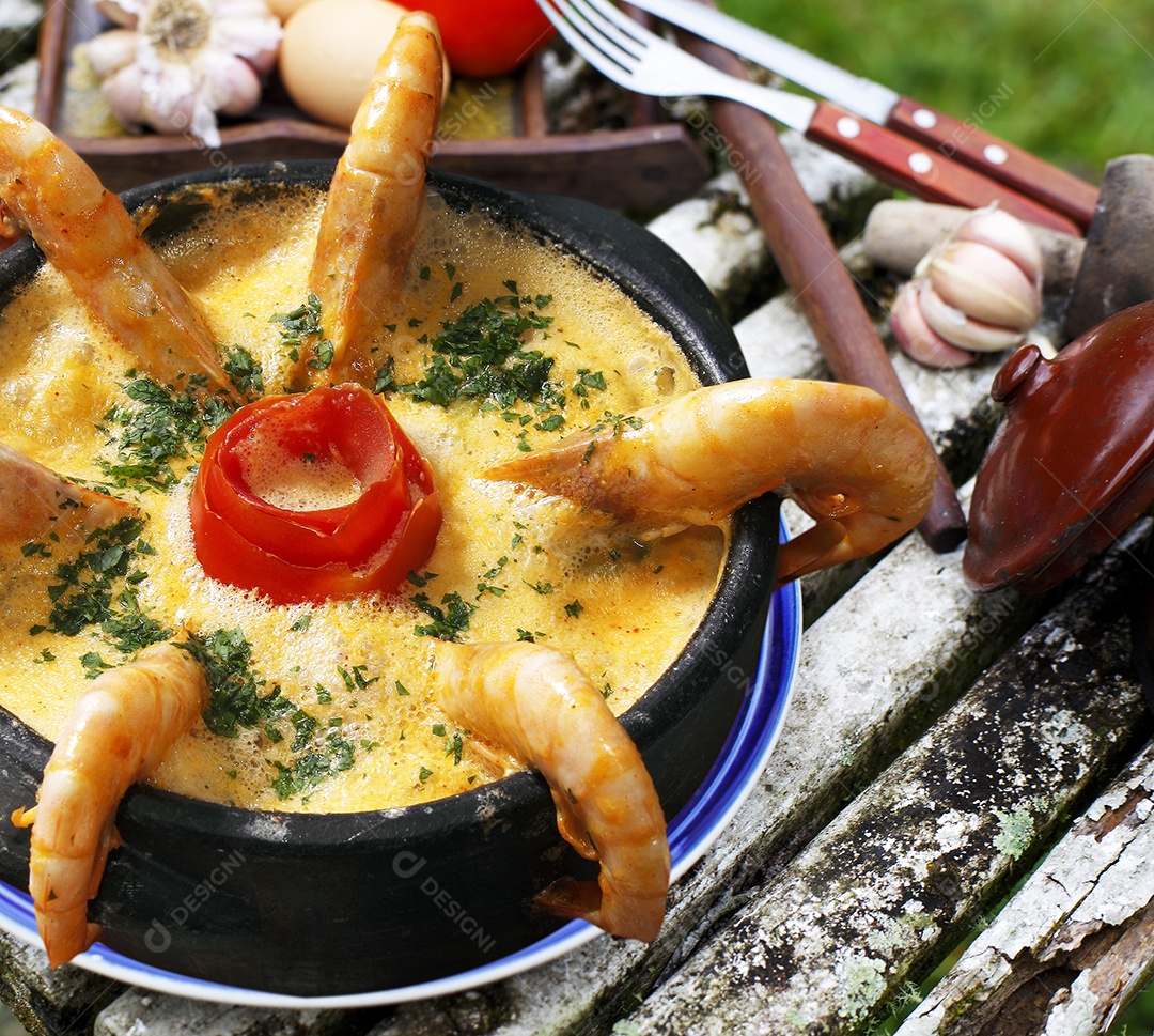 Moqueca de camarão e peixe em tijela sobre mesa de madeira
