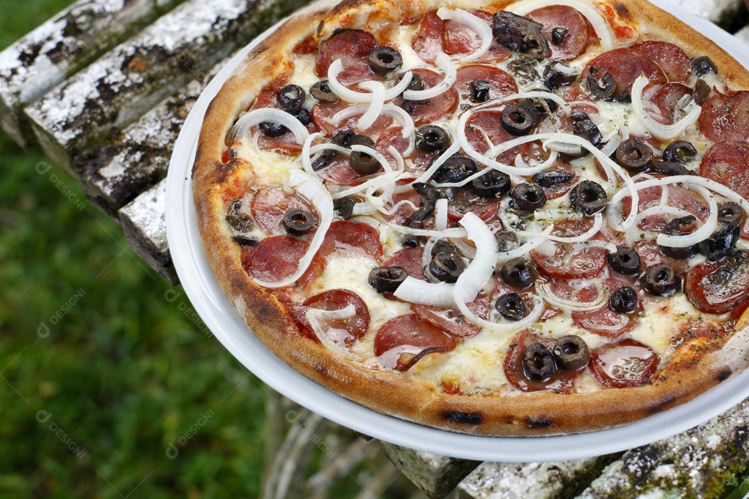 Pizza de calabresa com azeite sobre fundo desfocado