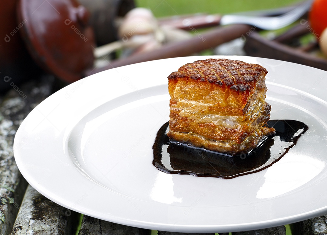 Carne de de porco assada ao molho em um prato sobre fundo desfocado