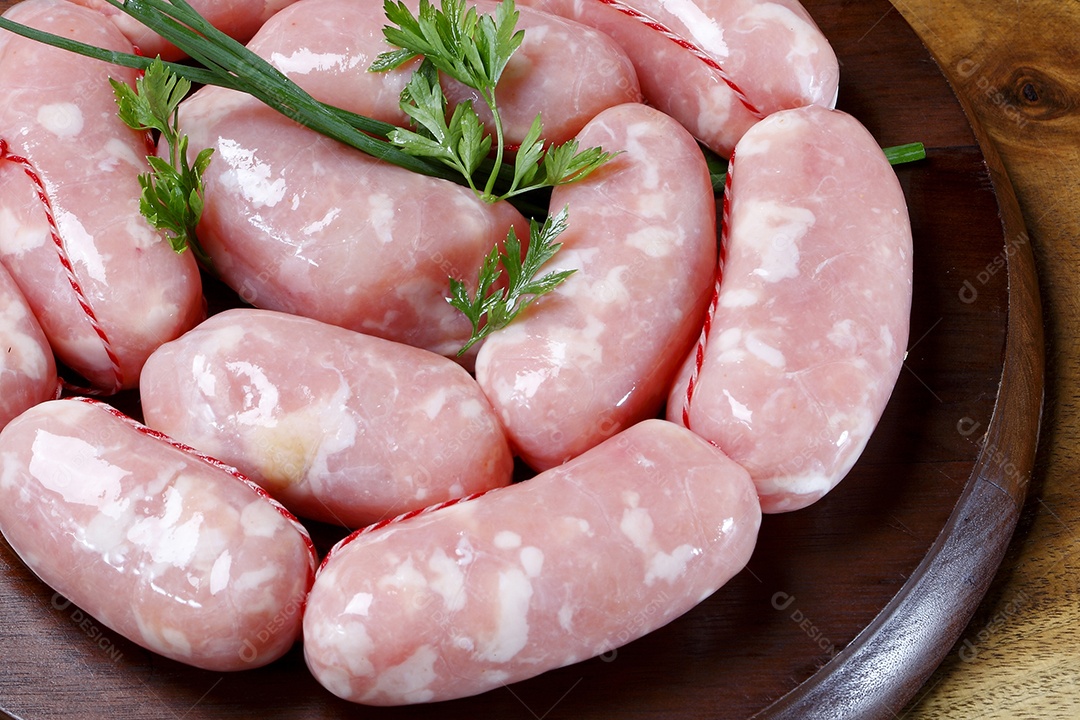 Linguiça caseira sobre tábua com hortaliças ao lado