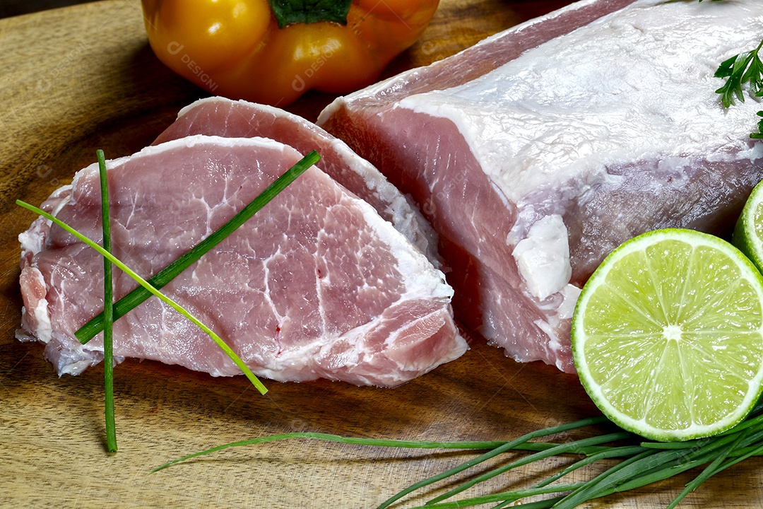 Carnes cruas sobre tábua com alguns temperos