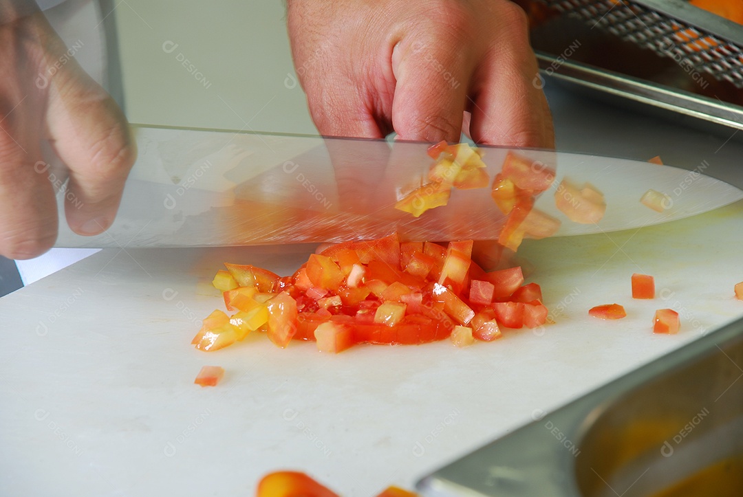 Mão com faca cortando pimenta