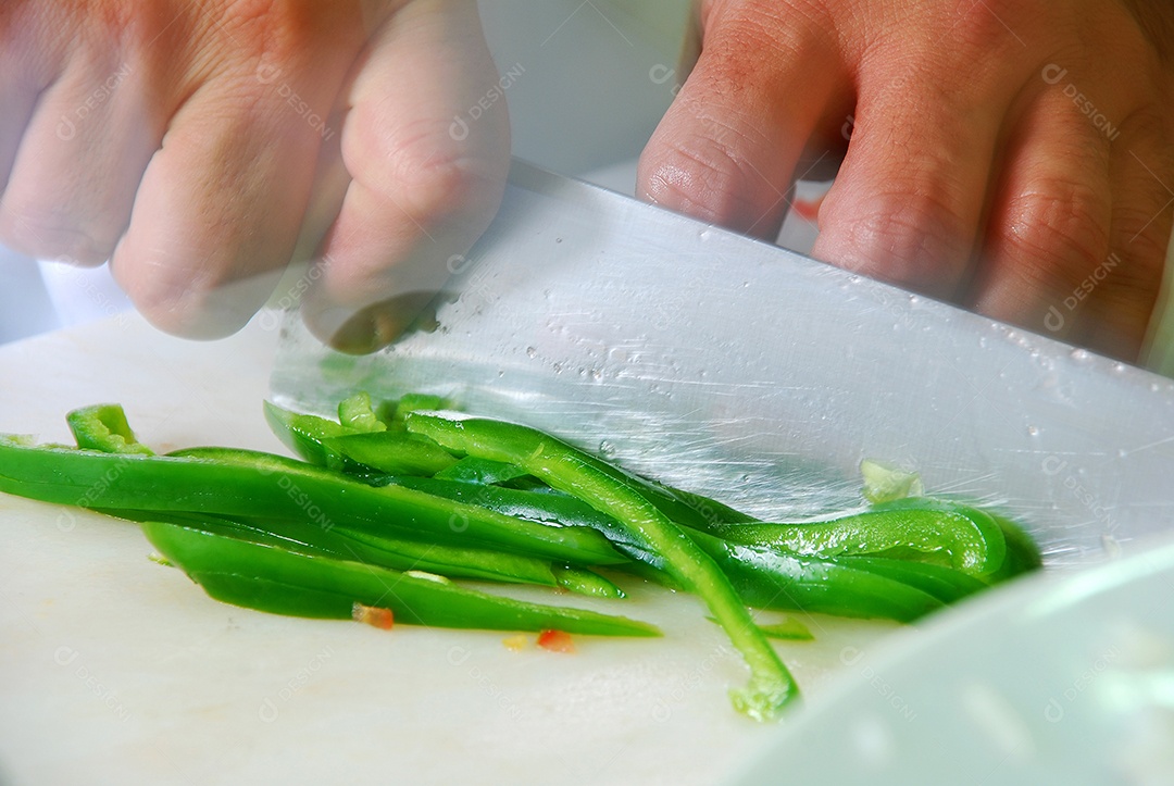 Mão com faca cortando pimenta