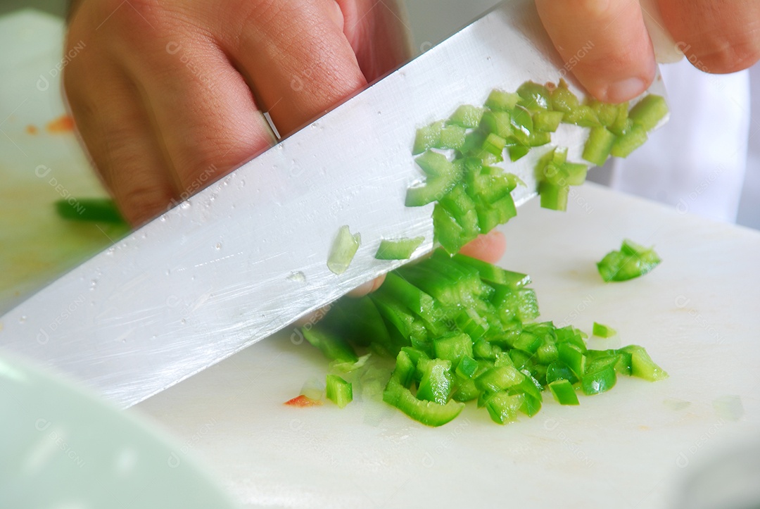 Mão com faca cortando pimenta