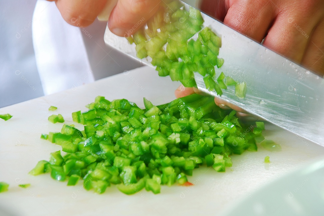 Mão com faca cortando pimenta