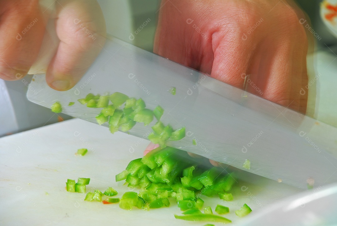 Mão com faca cortando pimenta