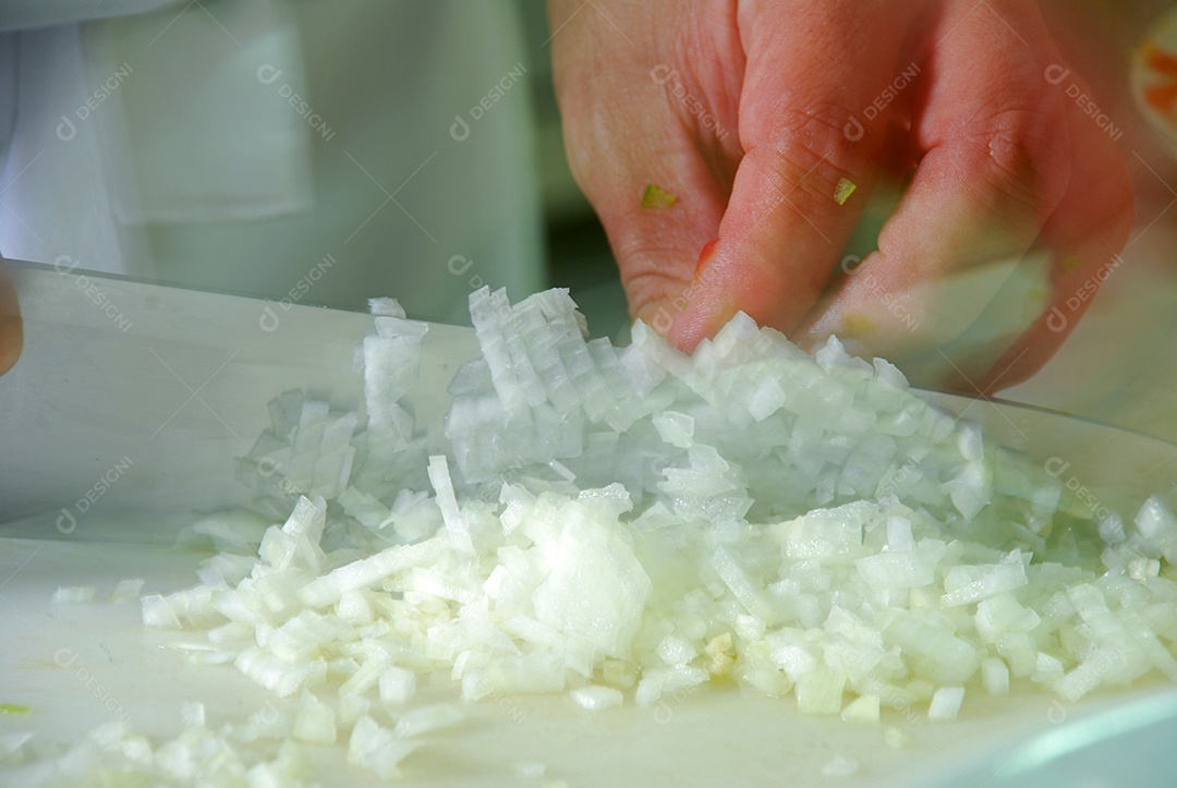 Mão com faca cortando cebola