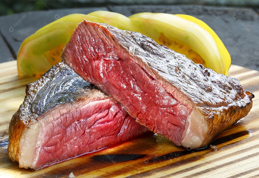 Carne assada e cortada sobre uma tábua com tomate