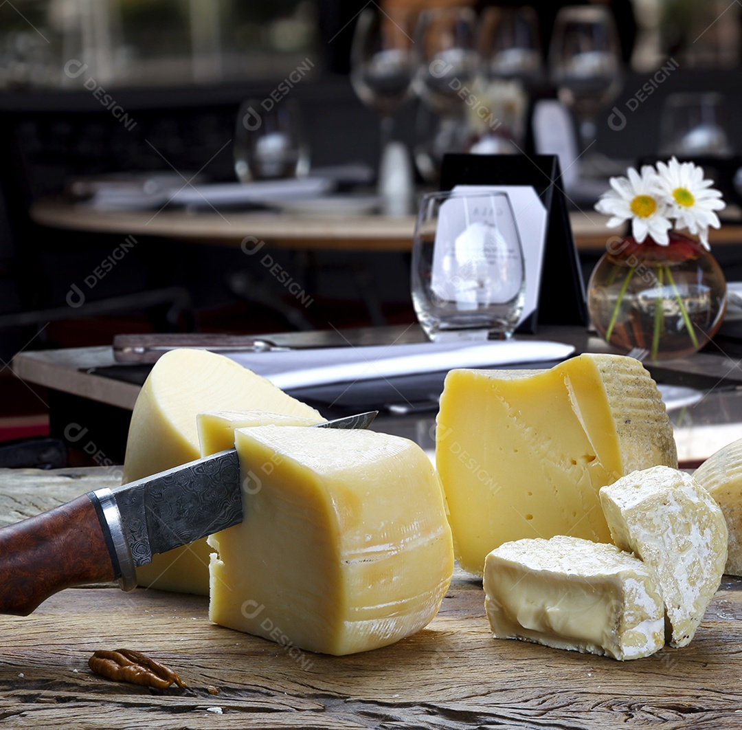 Mesa com queijos canastras e uma faca cortando