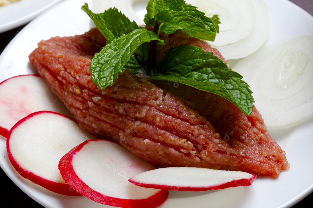 Quibe cru em um prato sobre mesa de madeira