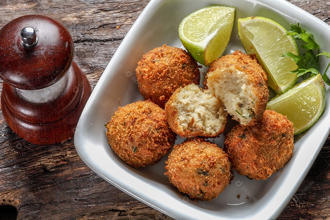 Bolinhos de bacalhau fritos servidos com limão e molho picante