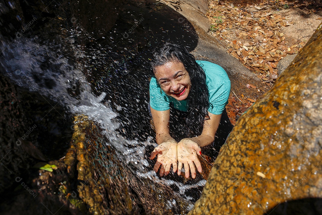Mulher bebendo água em um riacho cristalino