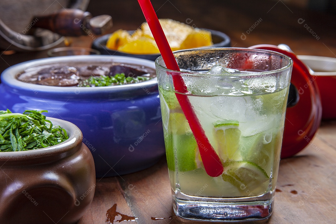 Caipirinha com feijoada sobre mesa de madeira