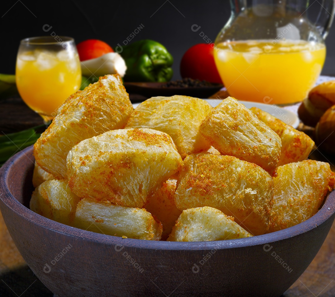 Mandioca frita em tijela sobre mesa de madeira