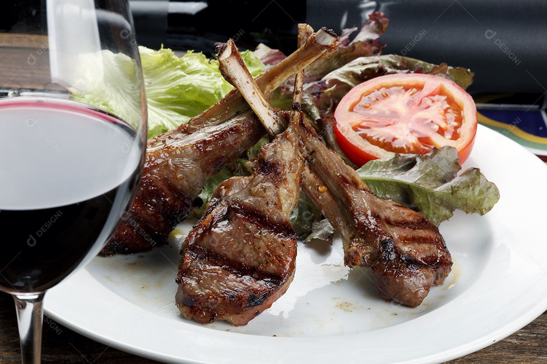 Costela de cordeiro assada com salada e taça de vinho