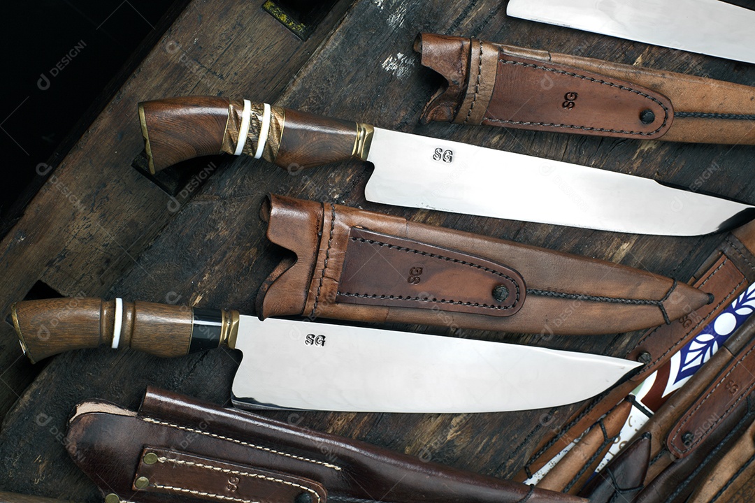 Facas afiadas com bainha de couro sobre tábua de madeira