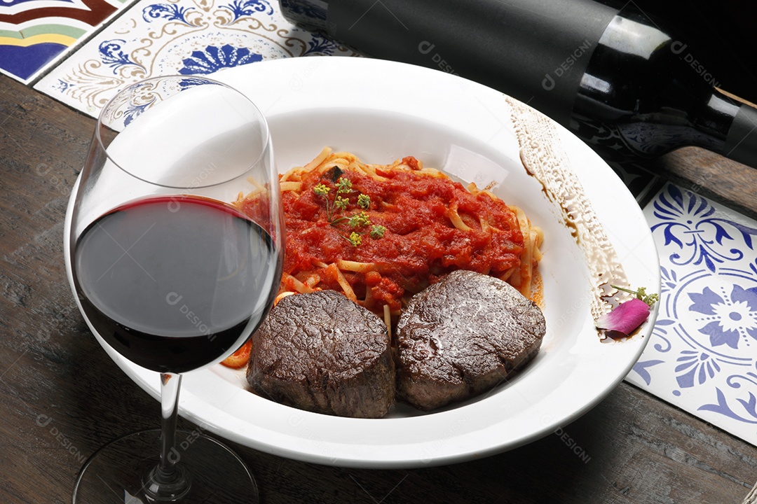 Macarrão espaguete ao molho e filé mignon com taça de vinho