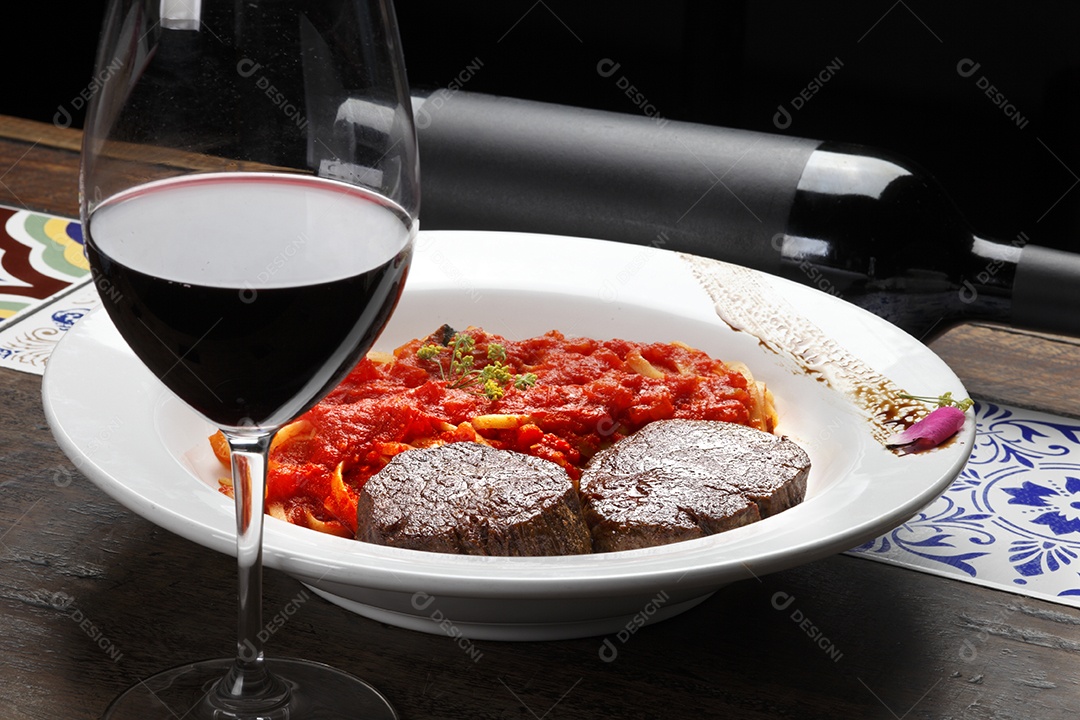 Macarrão espaguete ao molho e filé mignon com taça de vinho