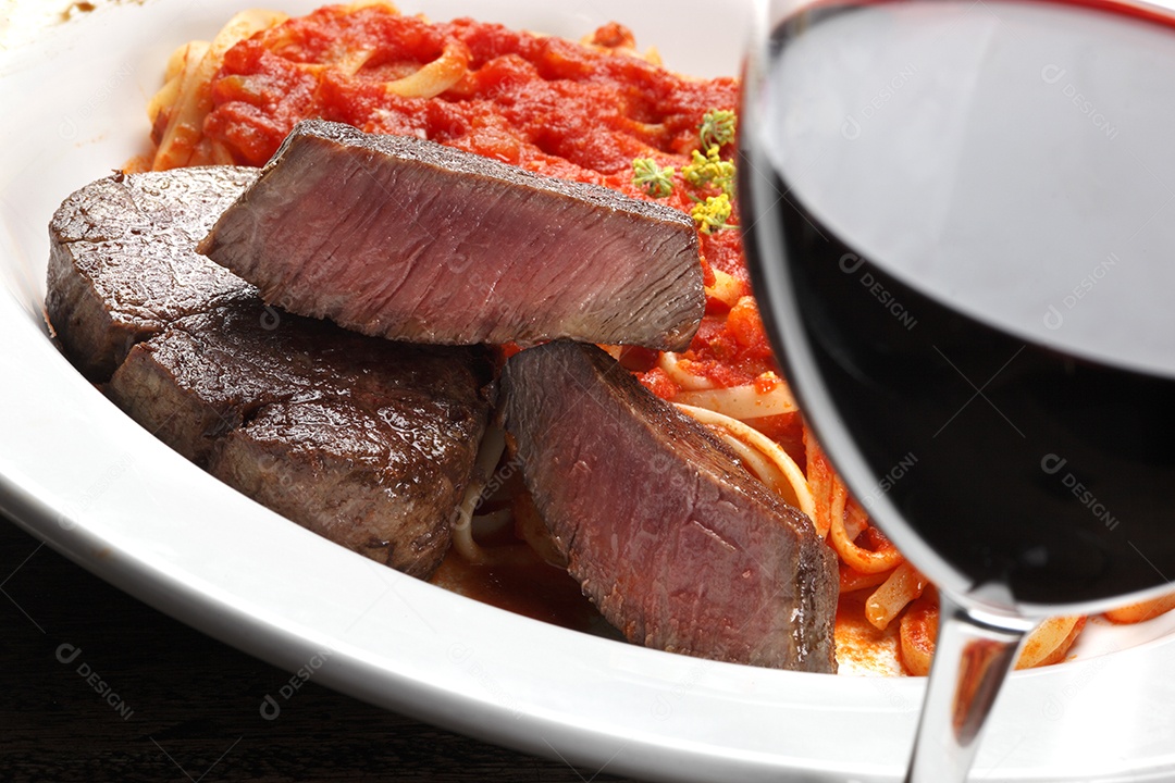 Macarrão ao molho e bife mignon delicioso com taça de vinho