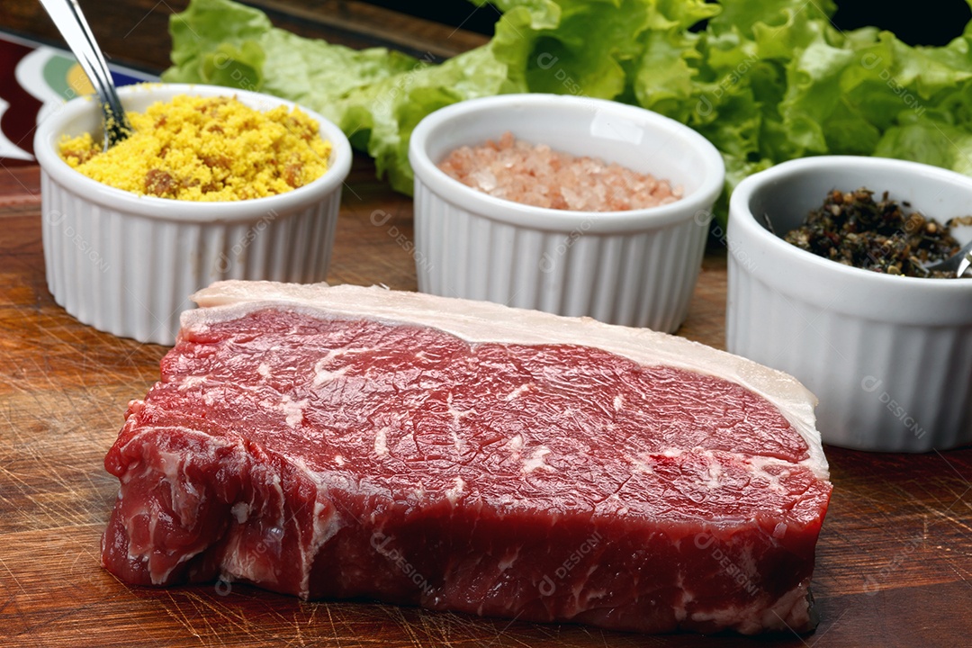 Bife cru com temperos sobre tábua de madeira